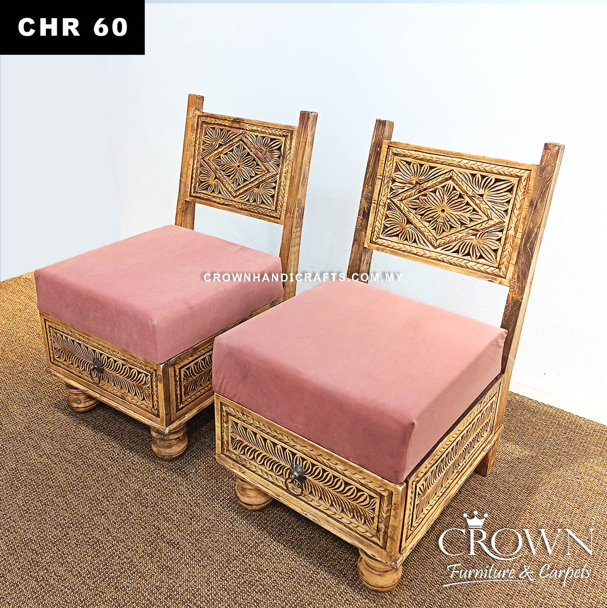 Pair of low wooden chairs with ornate carved panels and pink cushioned seats