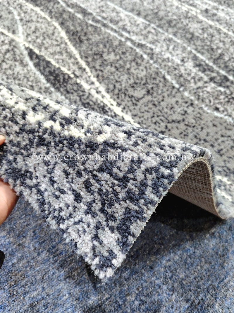 Rolled edge of speckled blue-gray rug with white and dark navy stripe pattern