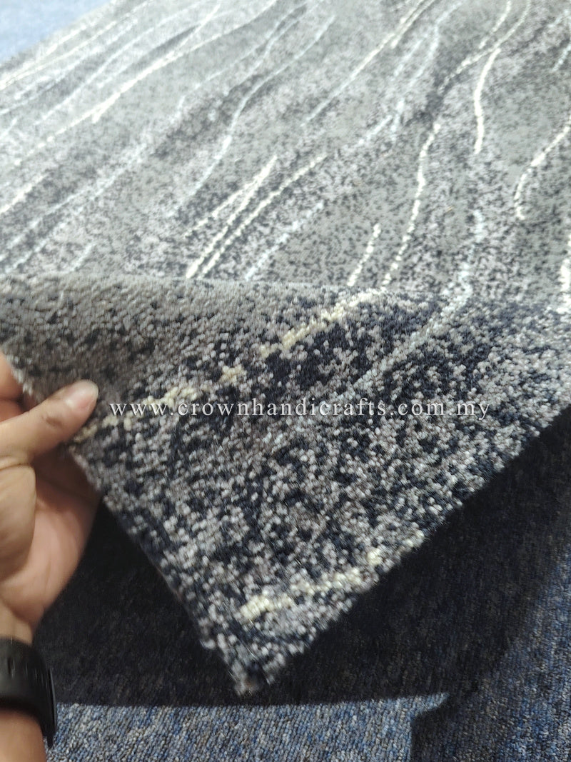 Abstract floor rug detail, dark blue-gray with speckled wave lines; frayed corner.