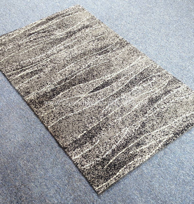 Abstract area rug with beige and dark speckled horizontal lines, angled view