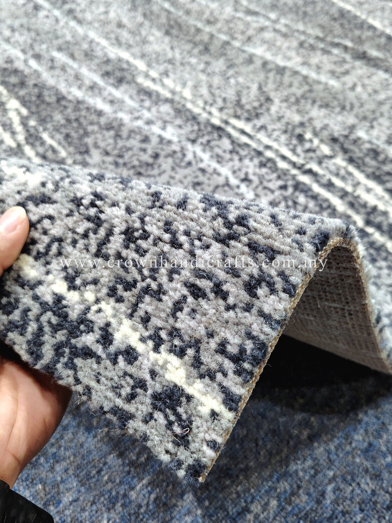 Abstract area rug with navy-gray and white speckled stripes, close-up curled edge