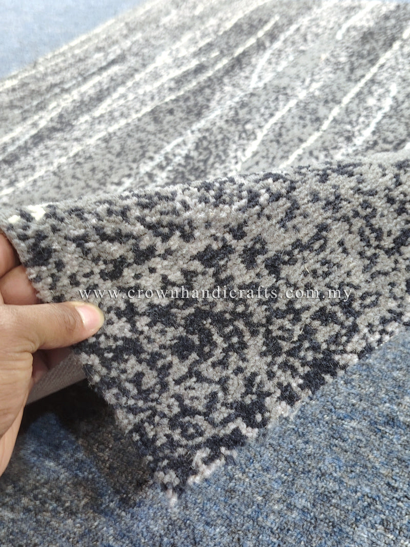 Abstract area rug with dark navy and light speckled texture, close-up edge curl