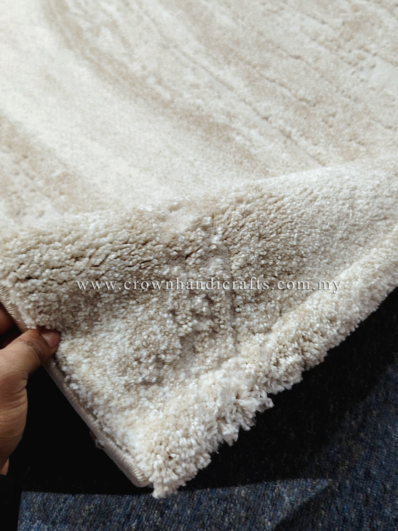 Cream area rug with dense short shag pile and textured abstract pattern