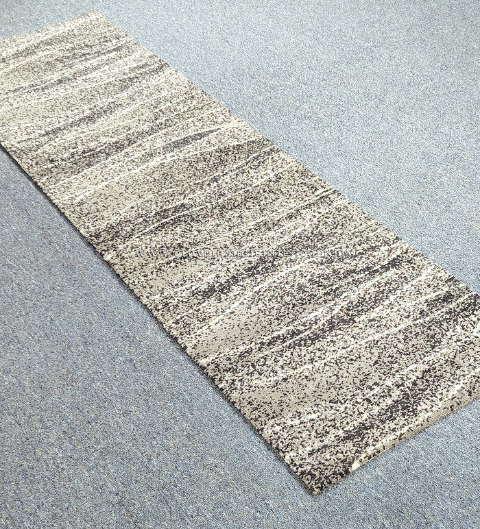 Narrow runner carpet with beige base, dark speckled horizontal stripes, angled view.