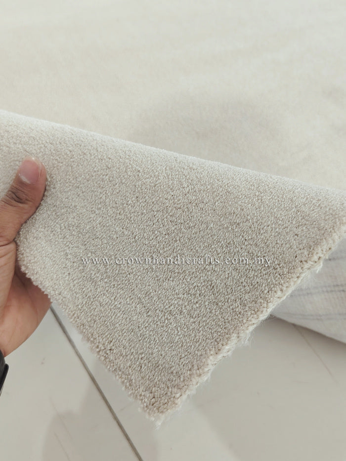Oatmeal beige runner rug corner with short fringe edge; hand showing the thickness.