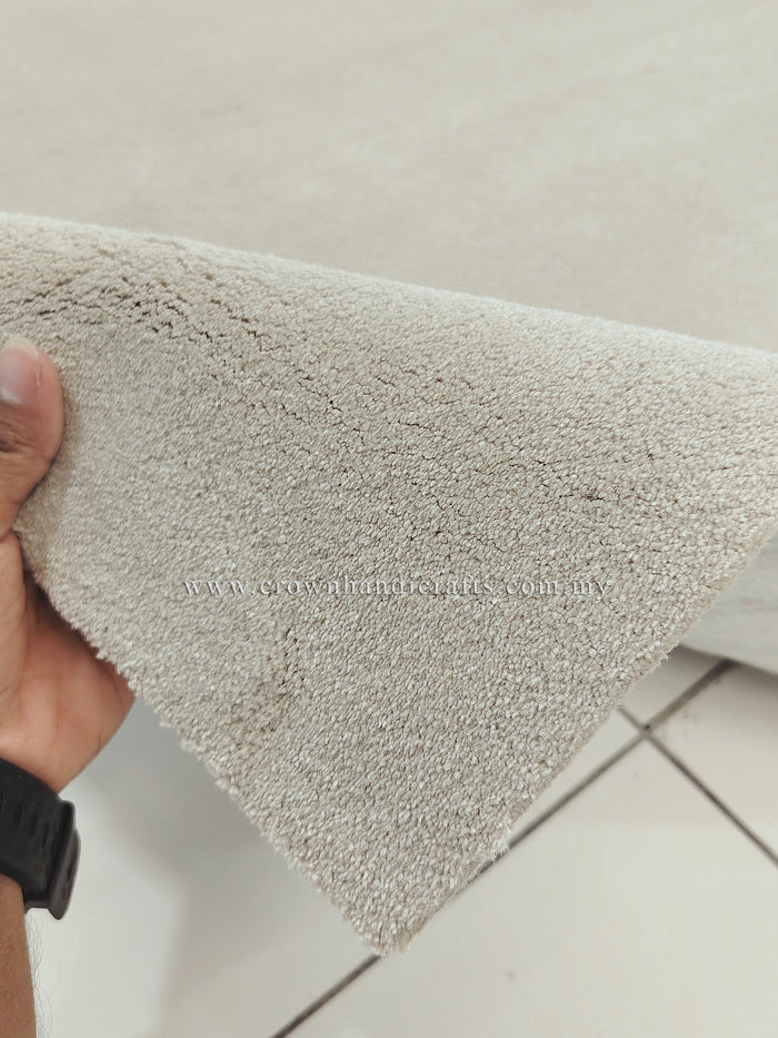 Oatmeal beige runner rug corner with short fringe edge; hand holding the rug tip.