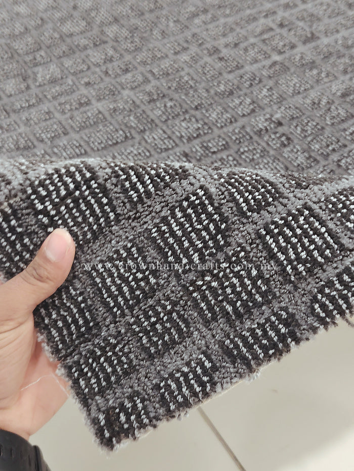 Dark grey rug corner detail with textured woven pattern and short fringe edge