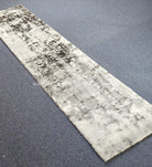 Light beige runner rug with dark mottled abstract pattern, short plush pile
