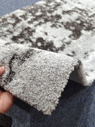 Runner rug edge with thick short pile and dark speckled abstract pattern