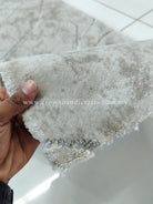 Hand holding the rug’s soft, looped beige pile edge with plush texture