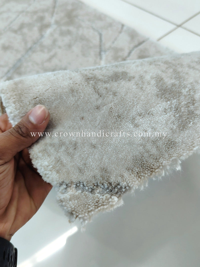 Hand holding the rug’s soft, looped beige pile edge with plush texture