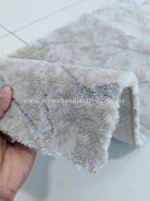 Close view of beige carpet runner edge showing dense, curly pile and stitched backing