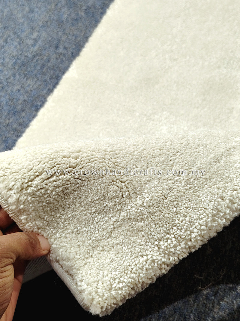 Cream runner rug edge close-up with thick shag-like pile and neatly bound seam.
