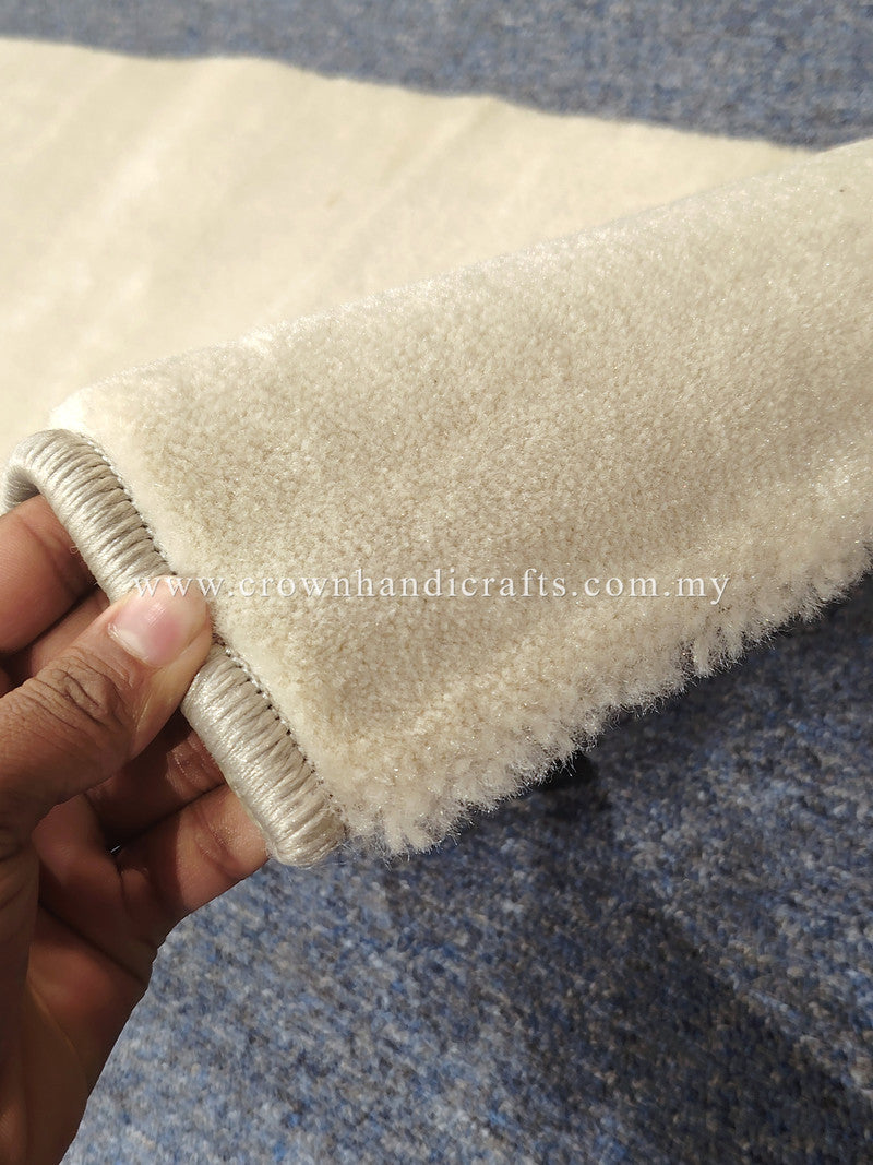 Cream rug edge with soft pile and stitched binding, close-up view