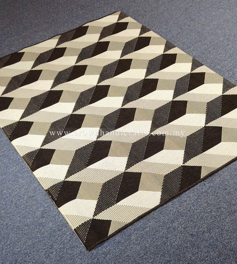 Geometric square area rug with cube blocks pattern in black, white and beige, corner view.