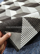 Geometric area rug with black, white and beige checkered pattern, textured woven edge.
