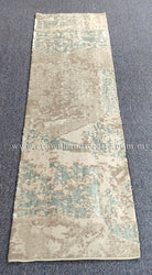 Beige runner rug with light teal distressed abstract design and narrow border