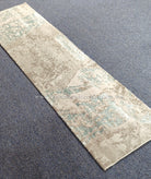 Beige runner rug with light teal faded pattern, flat weave design