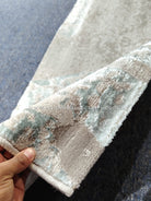 Beige runner rug edge with light teal distressed pattern and textured woven binding