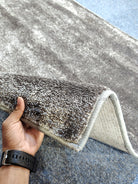 Dark gray runner rug edge with light backing, short textured pile visible