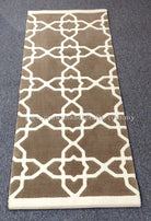 Slim runner rug with repeating white lattice motifs on grey-brown center and cream border.