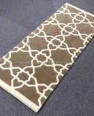 Rectangular runner rug featuring white lattice pattern on grey-brown with cream binding.