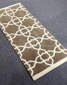 Grey-brown runner rug with bold white interlocking lattice pattern and cream border.