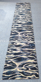 Narrow modern runner rug featuring high-contrast wave pattern in navy and beige tones.