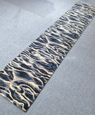 Wave-pattern runner rug with navy, cream, and beige tones; visible flat edge.