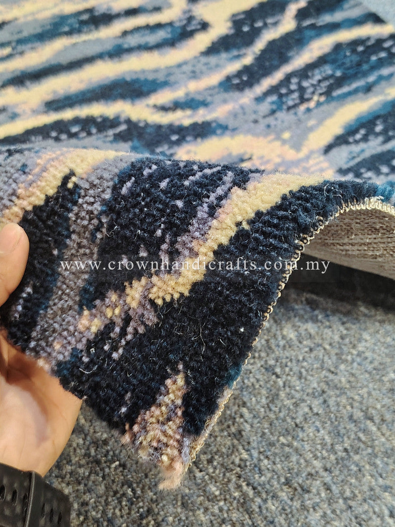 Hand-held close-up of wavy patterned runner rug fibers in dark navy and light beige.