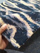 Close-up corner of wave-pattern runner rug with navy, cream, and pale yellow stripes.