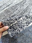 Abstract gray-blue rug with speckled navy and white stripe pattern, edge detail