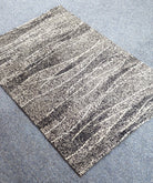 Abstract area rug with cream and charcoal horizontal striped pattern, flat lay