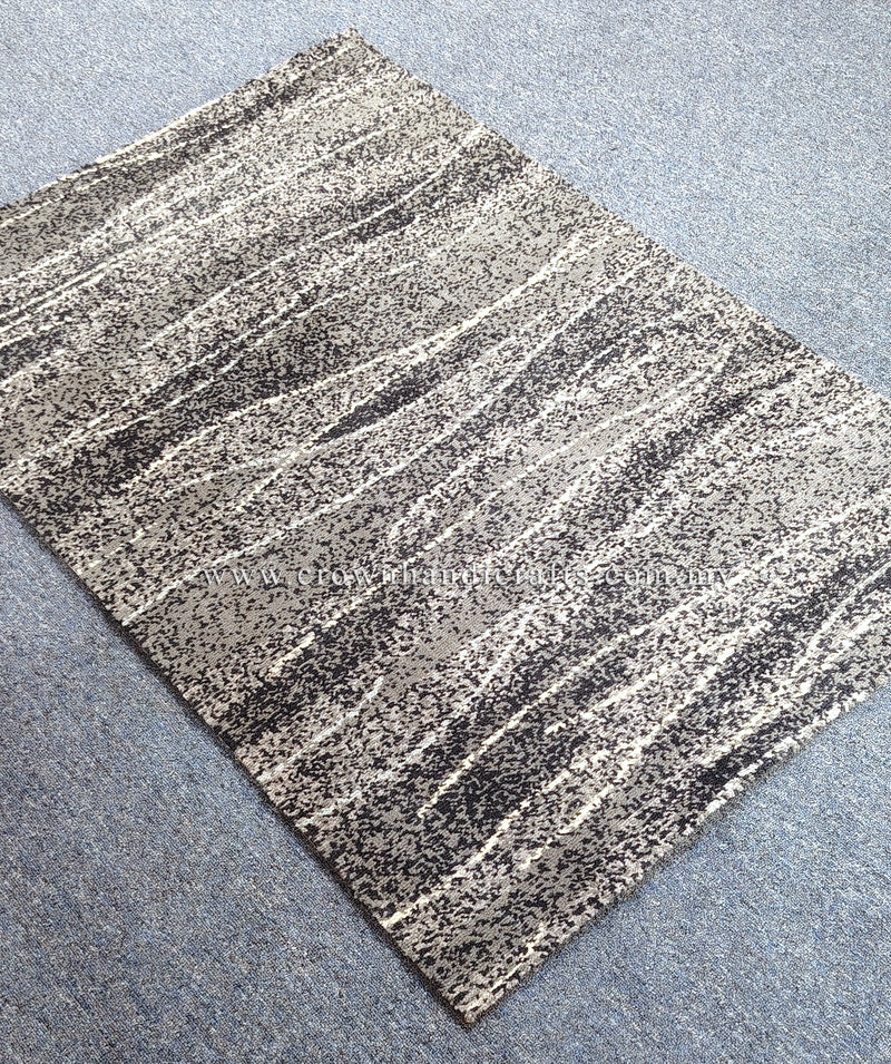Abstract area rug with cream and charcoal horizontal striped pattern, flat lay