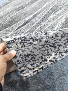 Abstract area rug corner detail, cream and dark charcoal speckled lines