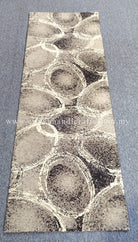 Slim runner rug featuring swirling abstract circles in beige, gray, and dark speckles