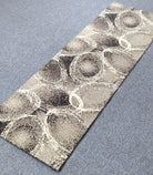 Abstract runner rug with textured circular rings, beige and gray with dark speckling