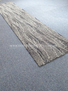 Extra-long abstract runner rug laid on surface, gray and cream wavy stripe pattern