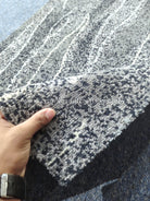 Abstract runner rug with charcoal and cream geometric pattern, corner close-up with hand
