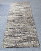 Abstract runner rug with beige and dark speckled horizontal stripe pattern, centered view