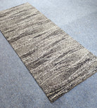 Abstract runner rug with beige and dark speckled horizontal stripe texture, corner view