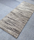Abstract runner rug with beige base and dark speckled stripe lines, angled view