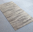 Runner rug with long abstract stripes in light gray and beige, flat lay view