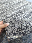 Runner rug corner detail with abstract dark speckled stripes and textured pile