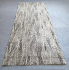 Abstract floor rug, light beige with white flowing line pattern and stitched border.