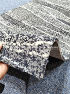Dark blue and cream speckled runner rug, close-up lifted edge with backing visible