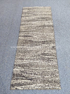 Runner rug: beige and black speckled abstract horizontal stripe pattern, straight view.