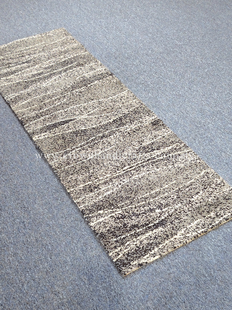 Runner rug: beige-and-black speckled abstract bands, textured flat weave, angled.