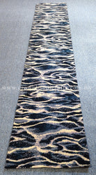 Rectangular runner rug with bold zebra wave pattern in navy and cream on light gray