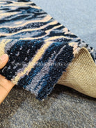Folded wave-pattern runner rug showing jute backing, navy and cream stripe design